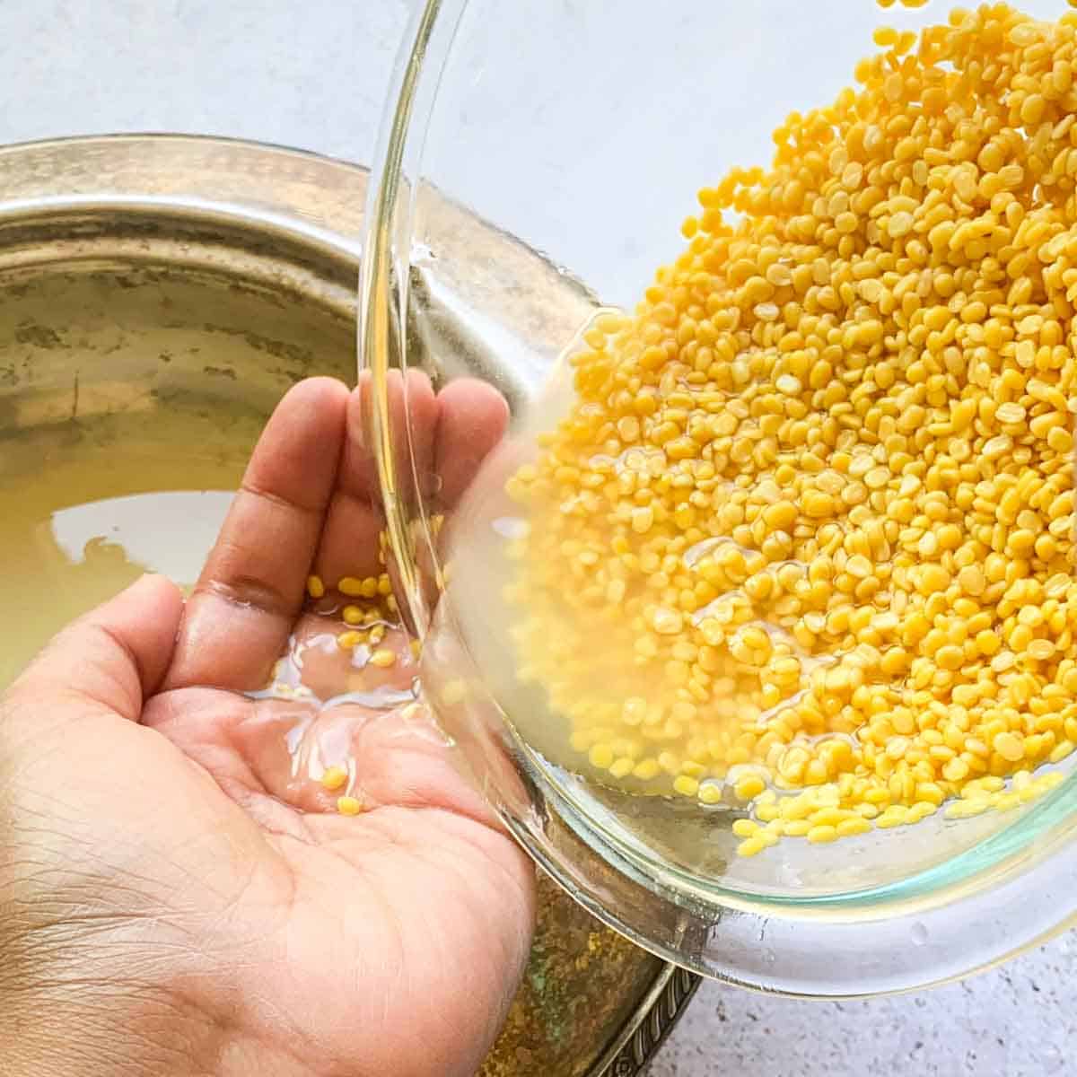 Moong dal being rinsed and drained to remove starchy and cloudy residue