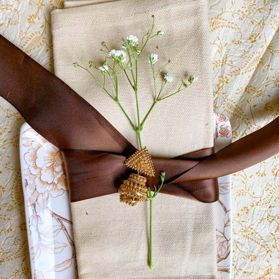 Napkin tied with a brown bow, baby's breadth flowers, and an Indian gold earring