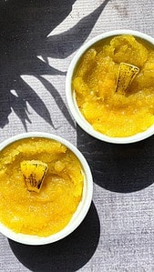 Pineapple kesari in white ramekins with charred pineapple slices and a shadow of pineapple