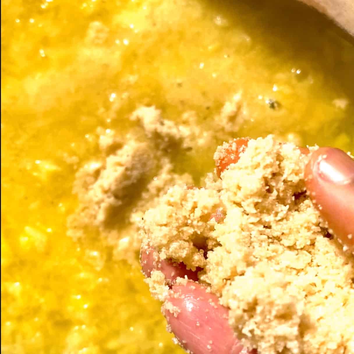 Hand adding roasted semolina into a pineapple sugar broth