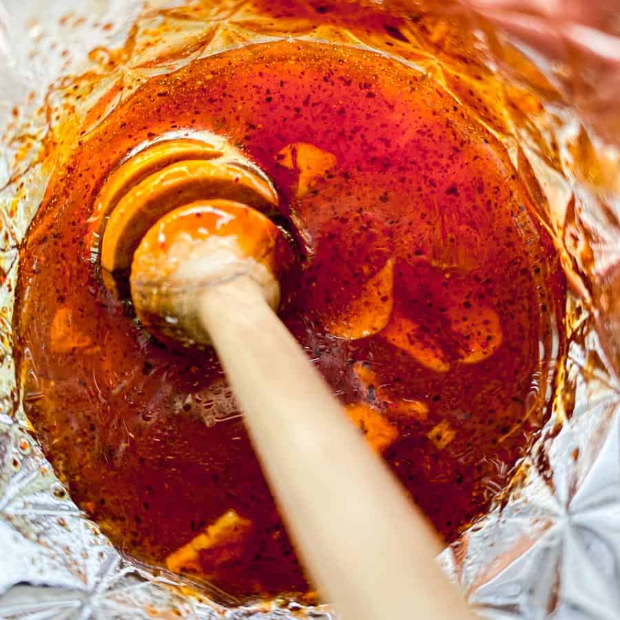 Kashmiri chili hot honey in a mason jar with a honey comb dipper