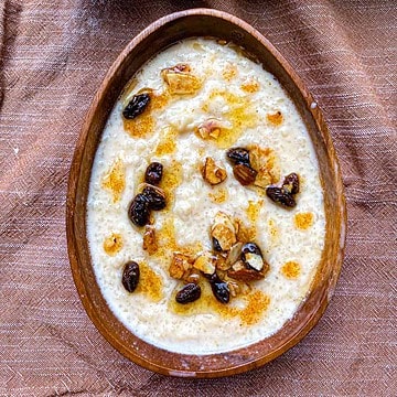 Rice Pudding in an oval bowl with ghee, raisins, and slivered almonds