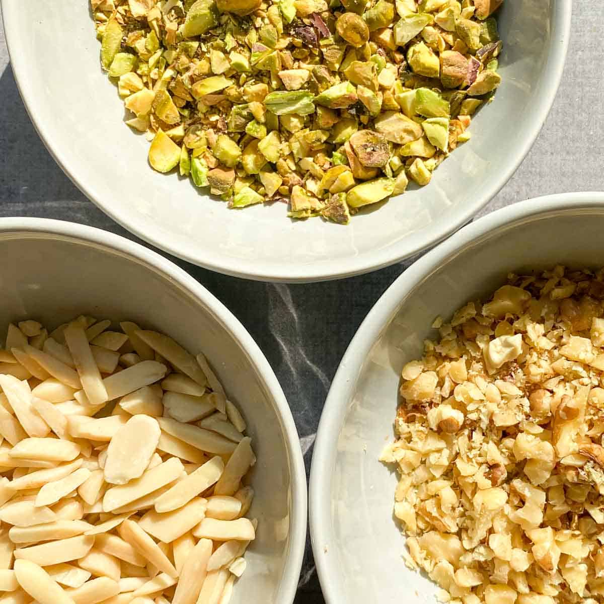 Bowls of pistachios, slivered almonds, and chopped walnuts