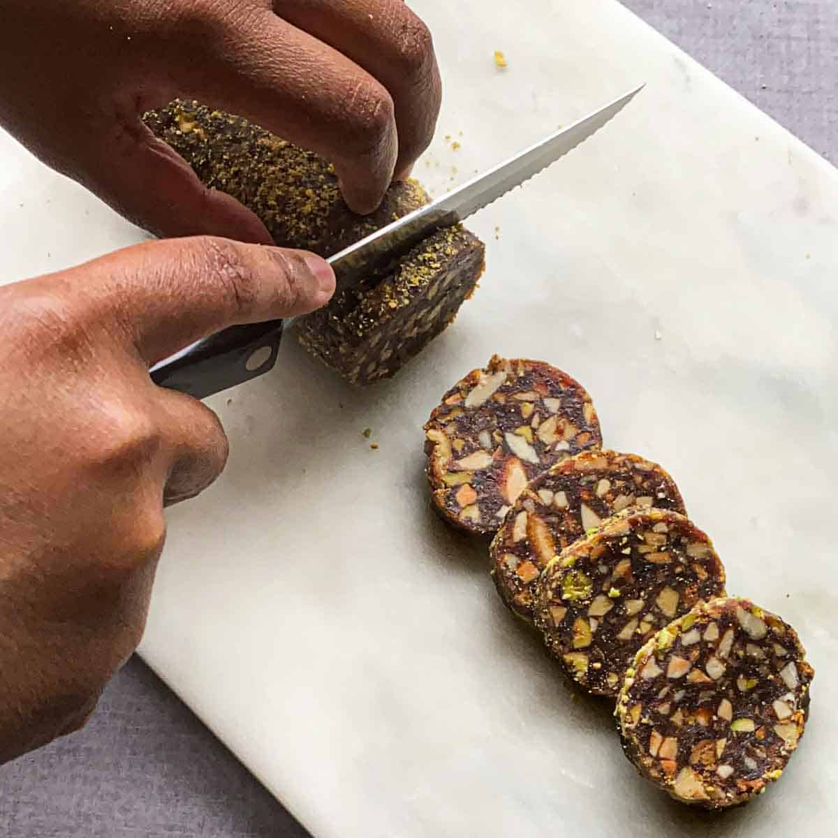 Serrated knife cutting khajur barfi log into slices