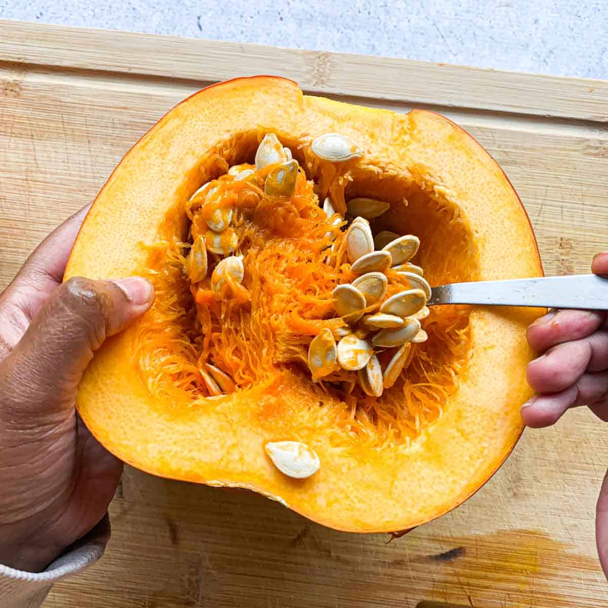 Scooping out seeds and insides of pumpkin half