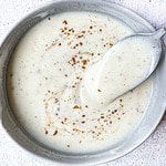 Dahi or Indian Yogurt Sauce for chaat with cumin powder sprinkled on top and a spoon scooping it out