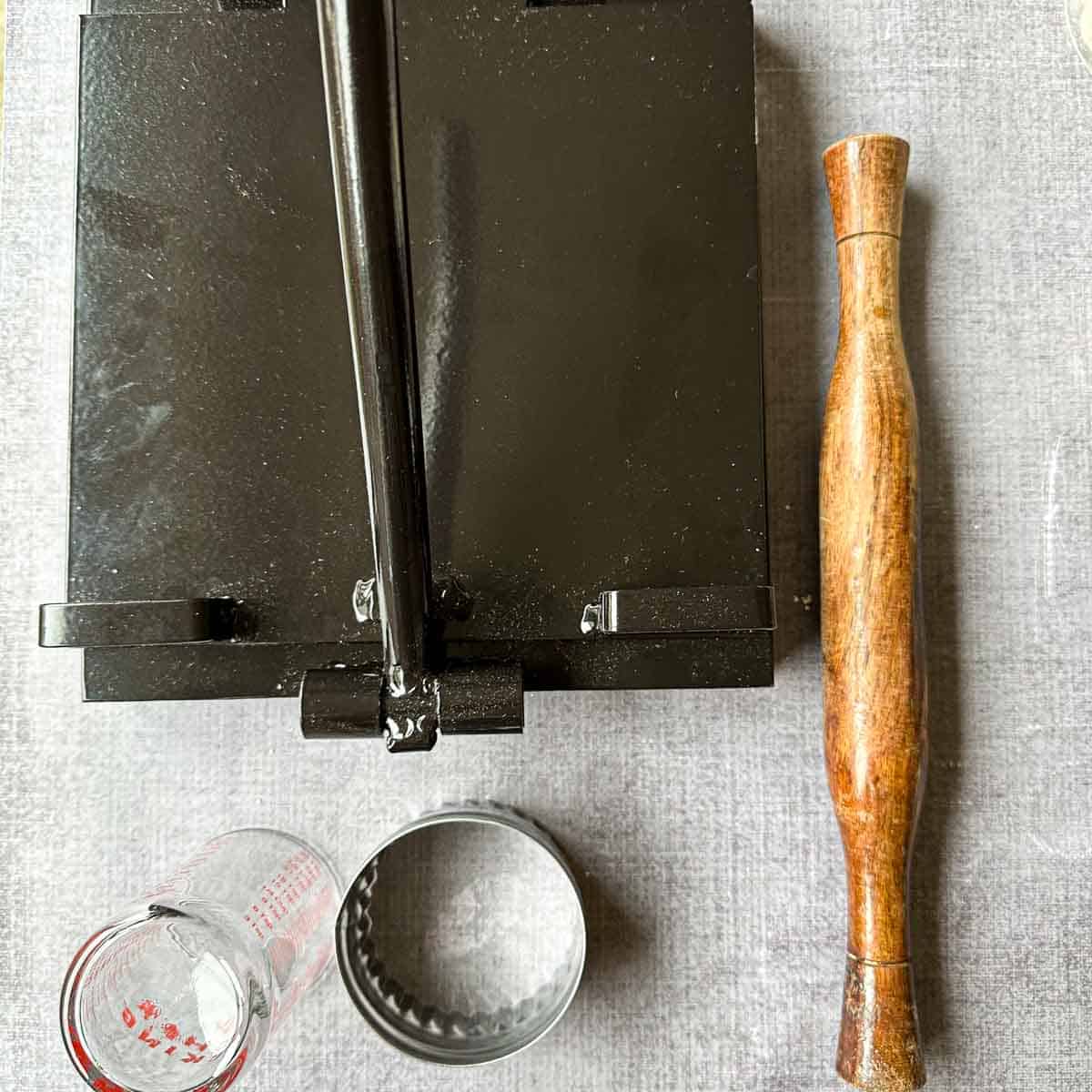 Picture depicting tools for rolling techniques for pani puri. It shows a tortilla press, a cookie cutter, a shot glass as alternative for cookie cutter, and a rolling pin