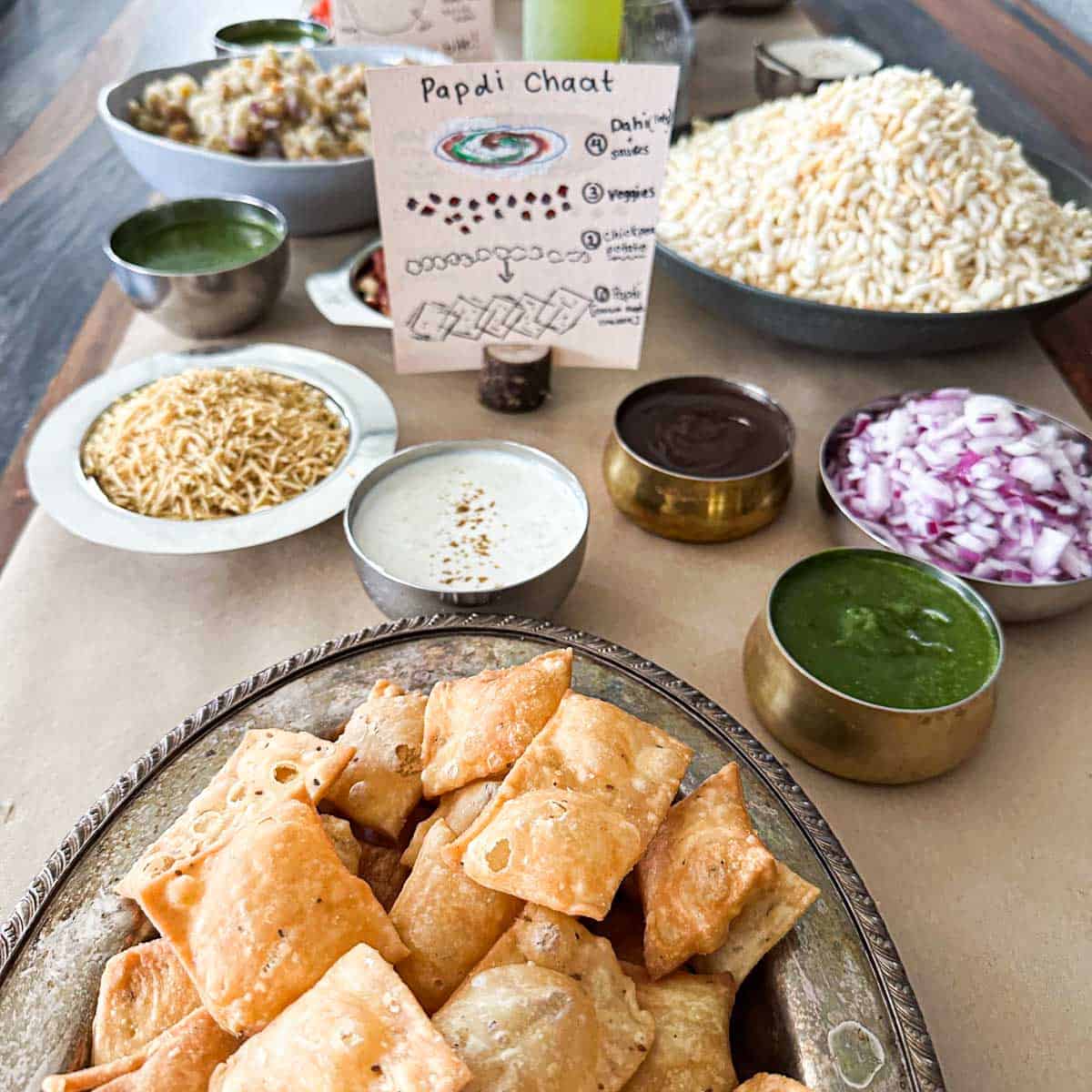 Table setup for chaat party. Table has chaat components like papdi crackers, chutneys, and decor for chaat party.
