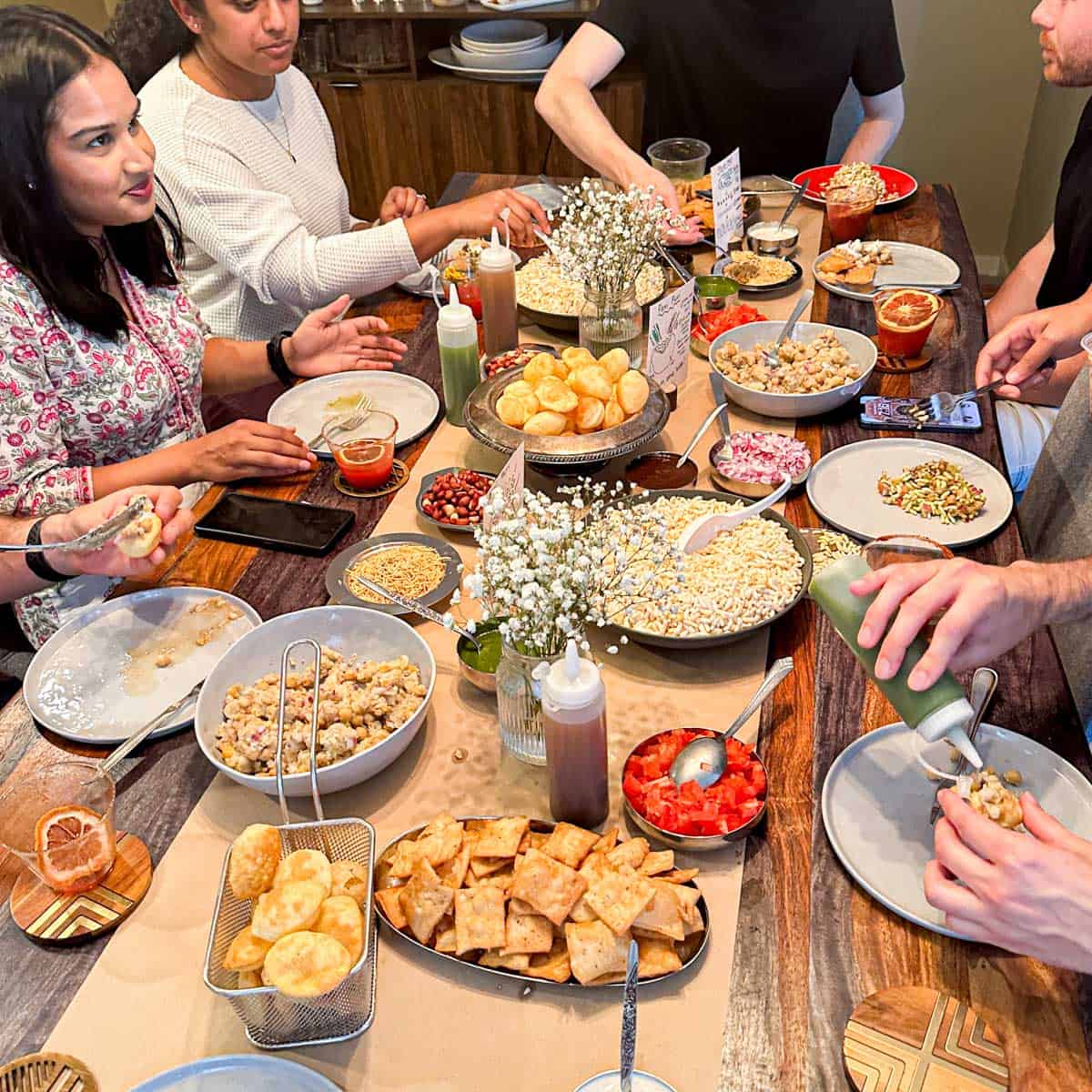 Friends gathering together at a chaat party with a chaat-cuterie board