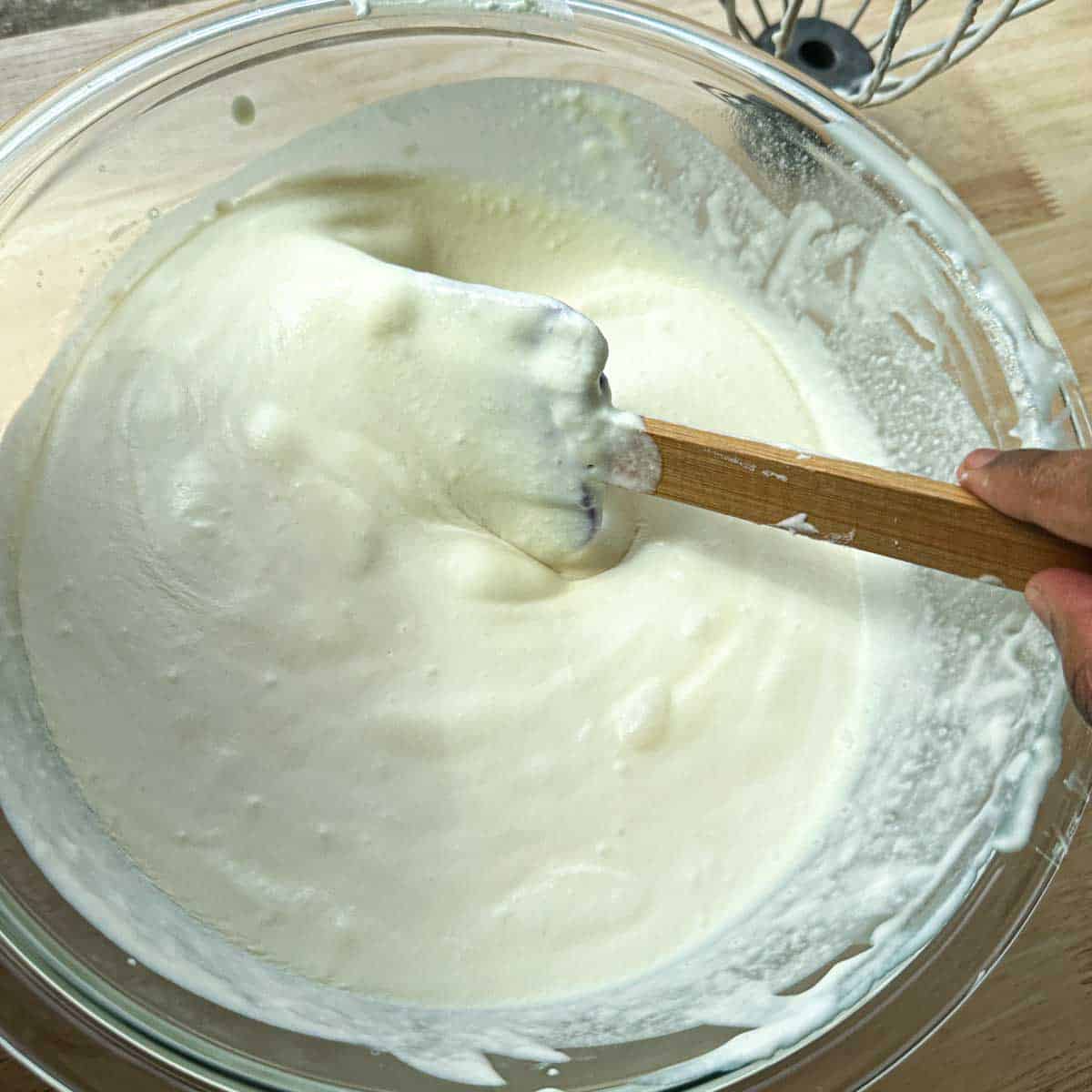 Whipped cream being folded into a thick base of condensed milk