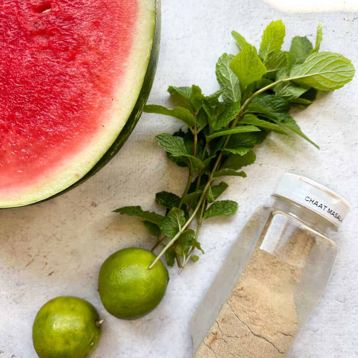 Ingredients for Indian watermelon drink with chaat masala, limes, mint, and watermelon.