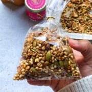 A brown hand holding a cellophane bag of chai spiced granola.