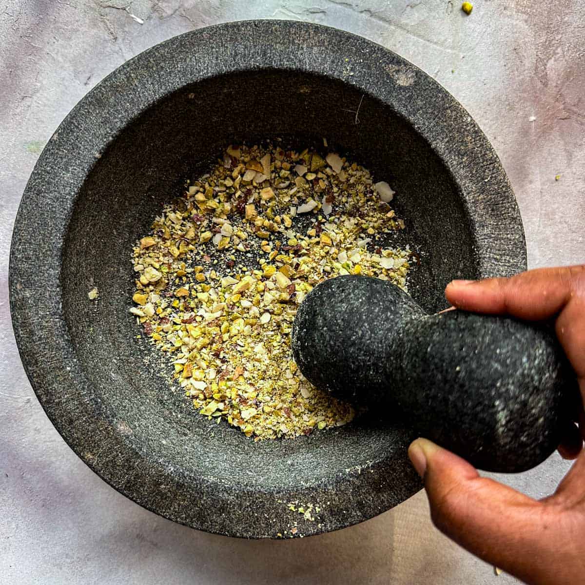 Crushed pistachios in a mortar and pestle