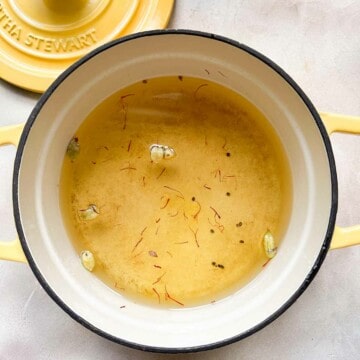 Pot with gulab jamun syrup made with saffron, cardamom, sugar, and water.