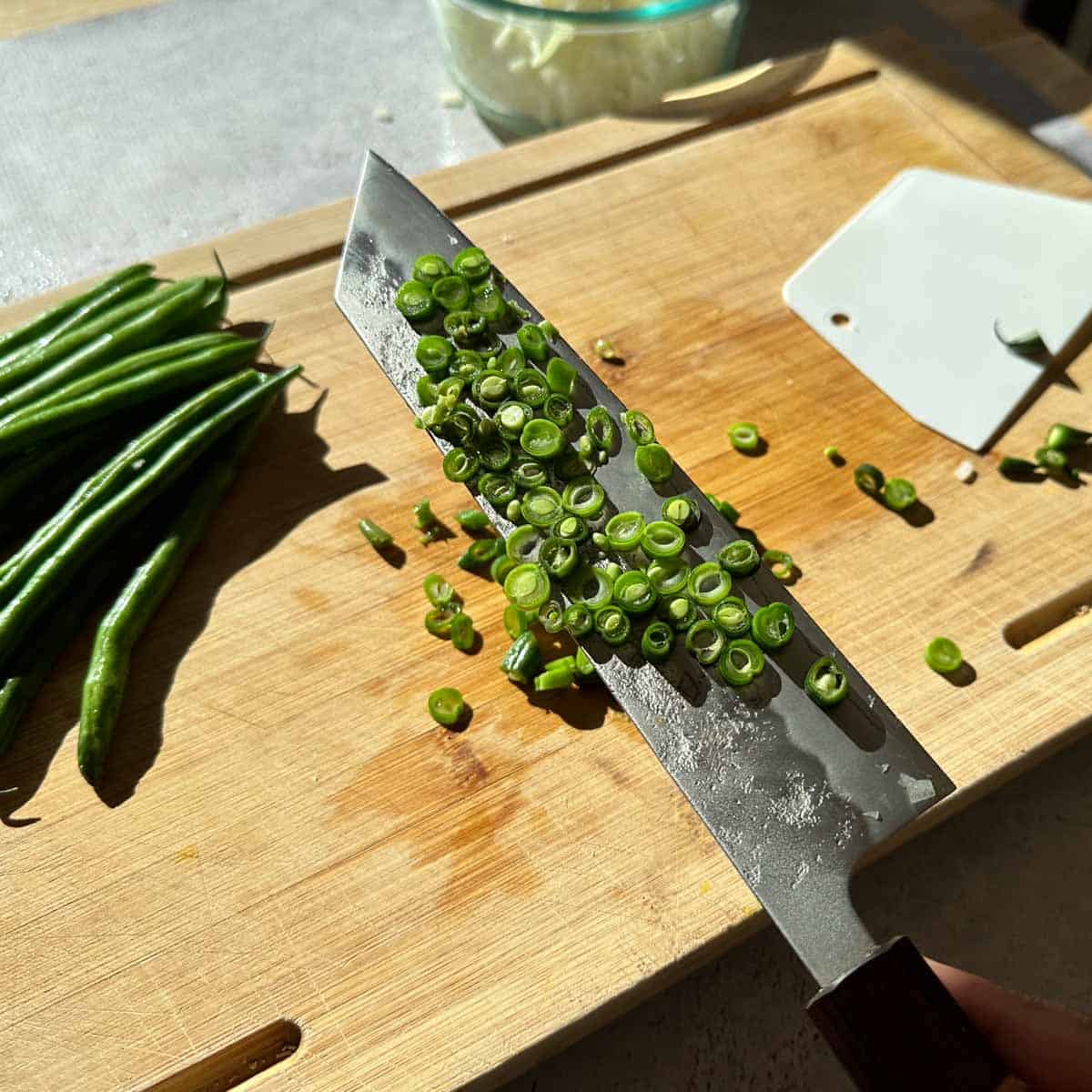 Thinly cut green beans on a cutting board