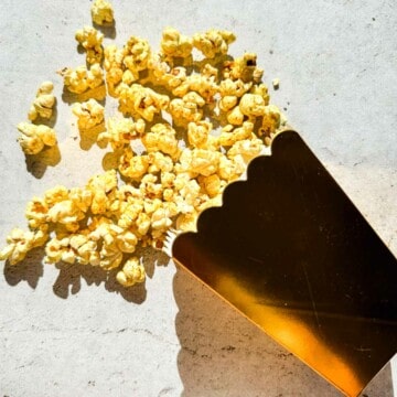 Indian masala popcorn falling out onto a counter from a gold popcorn container.
