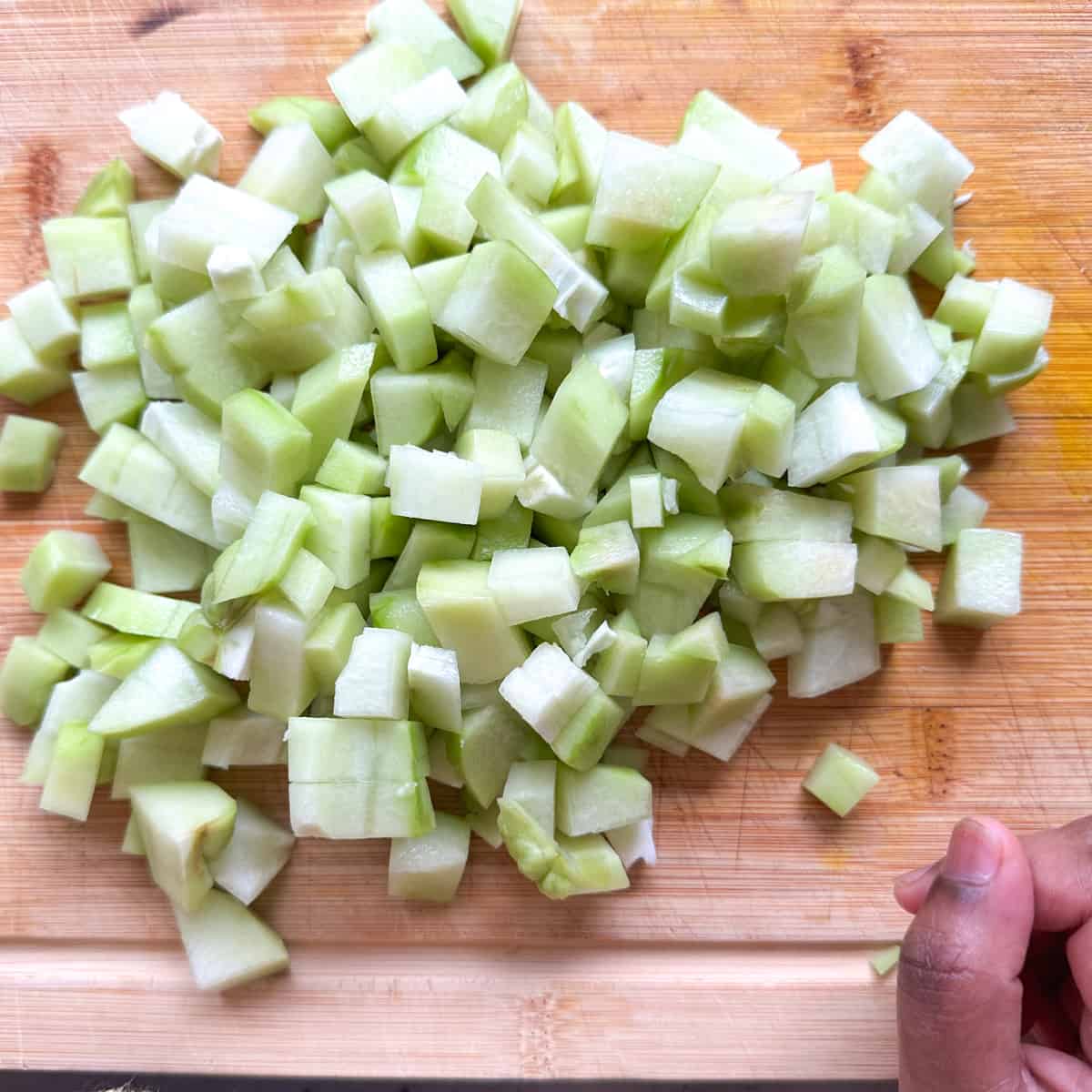 Chayote squash in cubes on a cutting board