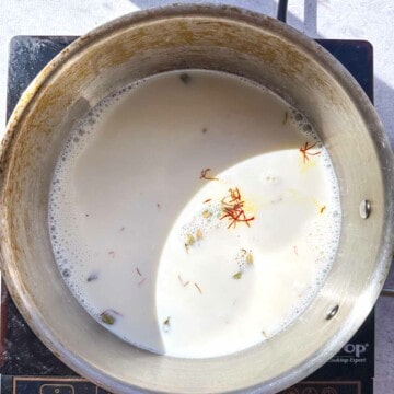 A saucepan with milk, saffron, cardamom, and sugar to make a saffron cardamom milk.