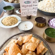 Table setup for chaat party. Table has chaat components like papdi crackers, chutneys, and decor for chaat party.