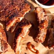 A parchment paper lined sheet tray with Indian style pork ribs with a tamarind date sauce