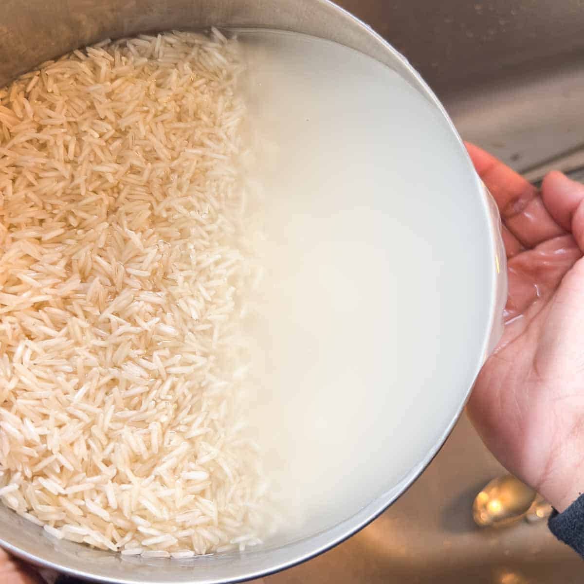 A hand rinsing and filtering out murky rice water.