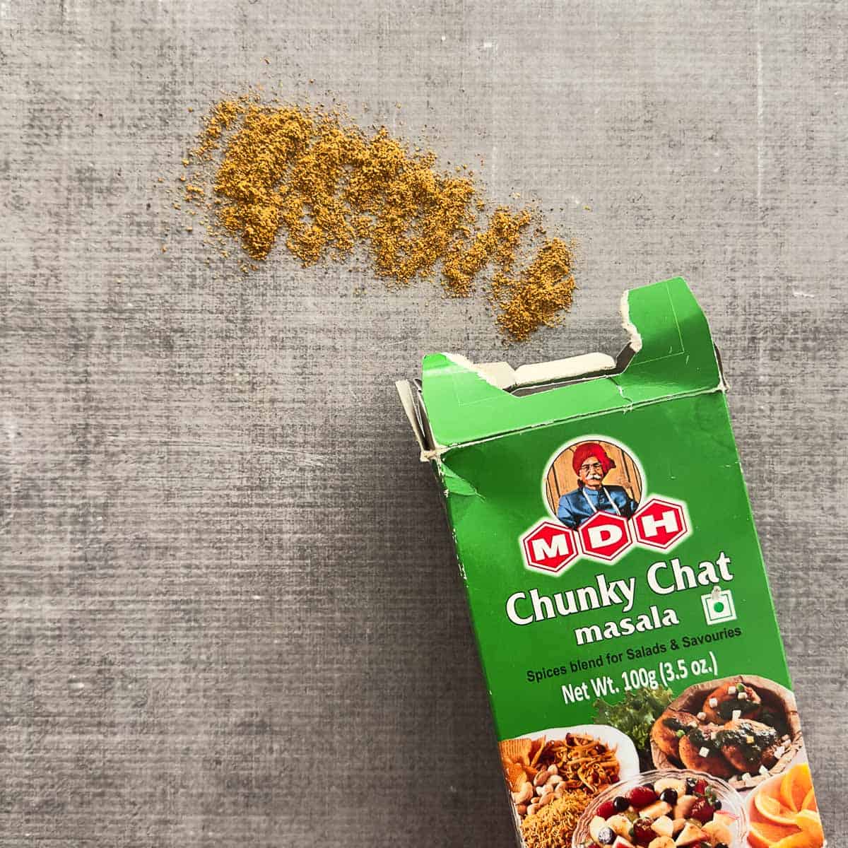 Chaat masala poured out of a spice container. The brand of chaat masala is MDH.
