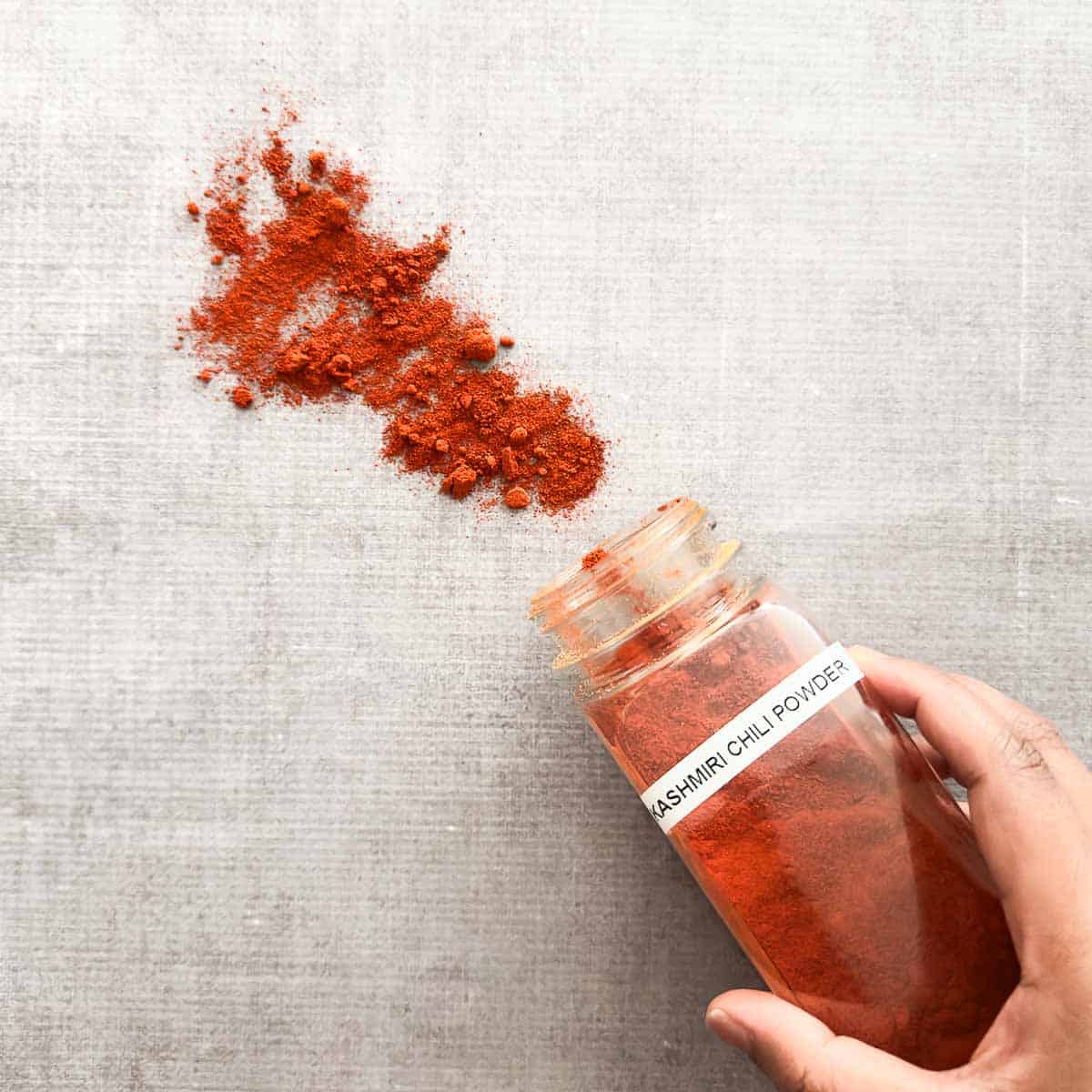 Kashmiri chili powder poured out of a spice container.