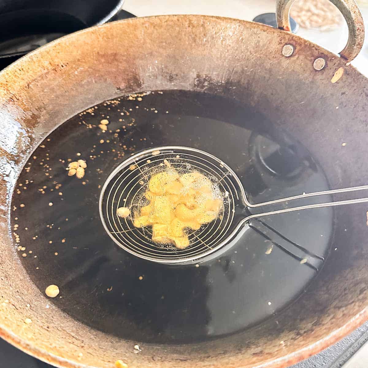 Cashews fried in a heat proof strainer basket.